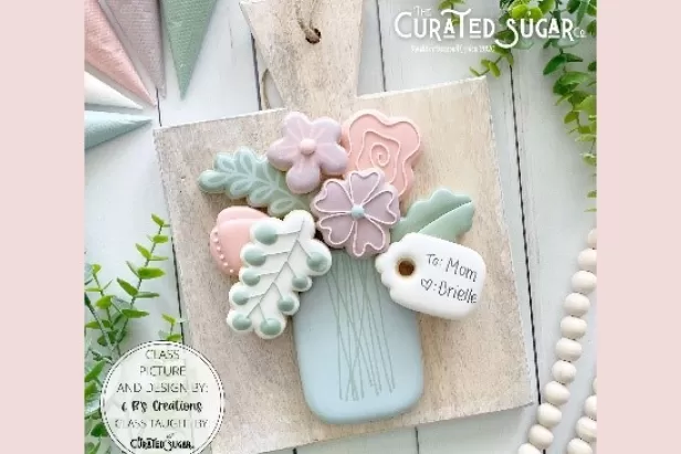 image of a blue vase, flowers and leaves all made out of decorated cookies
